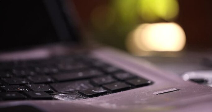 Close-up of a laptop standing on a table. The computer is smashed with a sledgehammer.