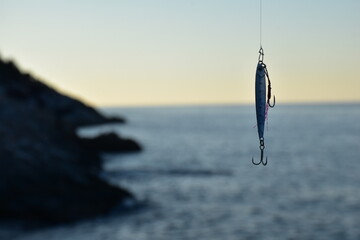 Metal fishing lure and a blur sea background - obrazy, fototapety, plakaty