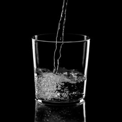 Vaso de crsital con chorro de agua sobre fondo negro