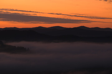Amazing landscape during a foggy morning with the sea of clouds overs forests at the bottom of the mountains. Beautiful nature of the world.