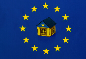 Small wooden house on the background of the flag of the European Union (EU). Сoncept of Ukraine's...