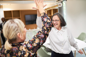 Two business women in the conference room giving a high five