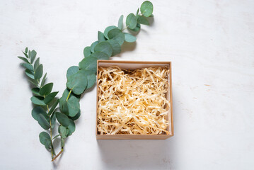 Obraz na płótnie Canvas Brown cardboard carton box with filler decorated with Eucalyptus green branch