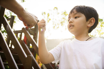 Happy Asian little boy enjoy playing and walking at the park with daddy.