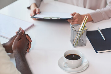 High angle shot of unrecognizable African American man sitting at table in front of his colleague...