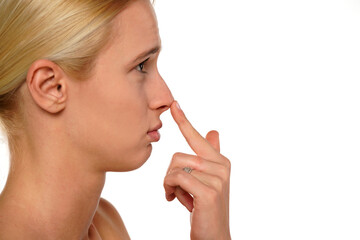 Young sad woman touches her nose with her finger