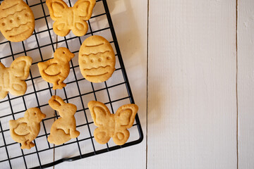 Cooked cookies in the form of Easter symbols cool down on a metal grate for baking.