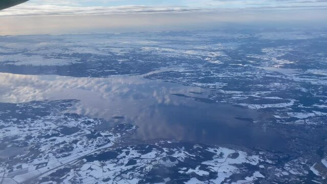 Flying over trondheim fjord with stunning reflection of the clouds on the water in a snow covered arctic landscape, panning right to left