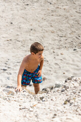 Little kid climbing a dune on a beach