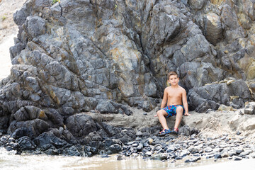 Little kid on a rocky beach at summer