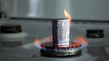 Concept of gas crisis. 500 euro bill is burning on a kitchen stove burner. European cash money....