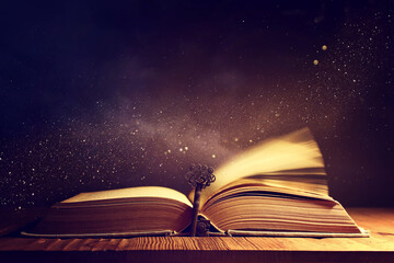 image of open antique book on wooden table with vintage key