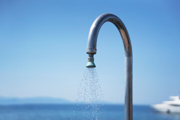Shower with flowing Water against the backdrop of an azure sea. 
