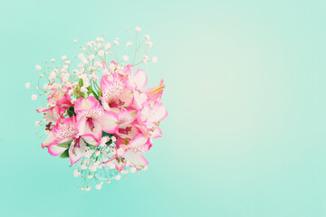 spring bouquet of pink flowers over wooden table and mint patel background