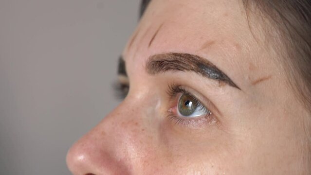 gloved hands wipe paint from eyebrows with a cotton pad close-up. eyebrow coloring and correction