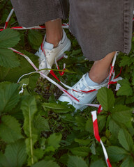 woman's legs in sneakers in grass with emergency tape