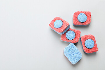 Many dishwasher detergent tablets on light background, flat lay. Space for text