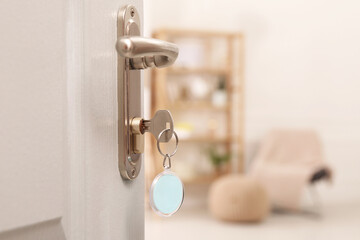 Open door with key in room, closeup. Space for text