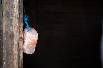 Big block of pink Himalayan salt hanging on a rope in a stable, for horses to lick it as an additive of minerals. Close up shot with copy space. - obrazy, fototapety, plakaty
