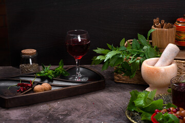 Still life with a glass of wine, fresh herbs, and a spice mortar.