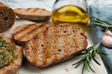 Tasty bruschettas with oil, rosemary and garlic on board, closeup