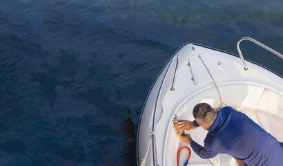A sailor washes his speedboat early in the morning before going to sea.