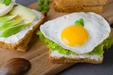 Sandwiches with curd cheese, fried egg, avocado and herbs