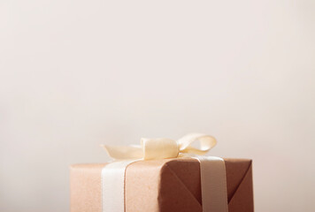 Gift box wrapped with craft paper and bow on neutral background