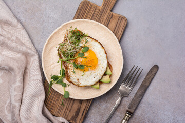 Tasty breakfast of fried egg on toast with avocado and microgreen