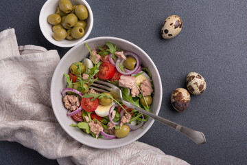 Healthy tuna salad with fresh arugula, cherry tomatoes, quail egg and olives