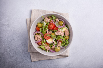 Healthy tuna salad with fresh arugula, cherry tomatoes, quail egg and olives
