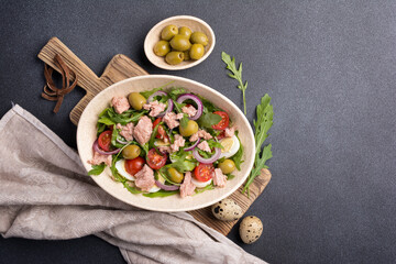 Healthy tuna salad with fresh arugula, cherry tomatoes, quail egg and olives