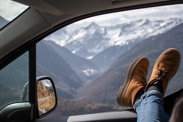 woman legs resting on the window of a van with views of snowy mountains in the pyrenees - obrazy, fototapety, plakaty