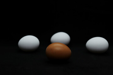 White and brown chicken eggs on a black background
