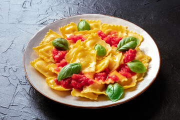 Ravioli with red tomato sauce and basil, vegan Italian dinner on a black slate background