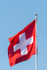 Schweizer Flagge im Wind vor blauem Himmel