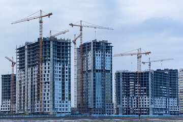 Construction site of multi-storey houses and building cranes