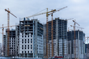 Construction site of multi-storey houses and building cranes