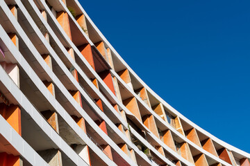 Curved old orange building against blue sky.