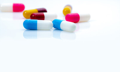 Selective focus on blue-white antibiotic capsule pills on white background. Prescription drugs. Colorful capsule pills. Antibiotic drug resistance concept. Pharmaceutical industry. Superbug problems.