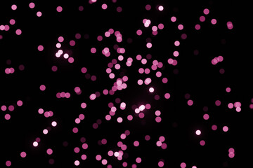 Defocused bokeh lights on black background, an abstract naturally blurred backdrop for Valentines Day or birthday party. Festive light texture. Violet blue garland in blur. Color 2022