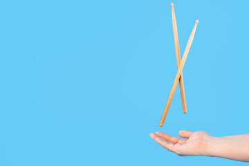 Close up male hands holding drumsticks on an isolated blue background. Concept of drumming lessons, online courses and learning at home. Favourite hobby. Background with copy space