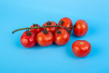 Bunch of fresh, red tomatoes with green stems flat lay isolated on blue background. Concept recipe, italian food, ingredient, juicy, nutrition, vitamins.