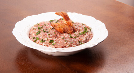pork meat risotto with pork rinds and green onions angle view on wooden table