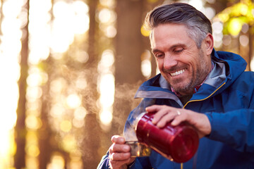 Mature Retired Man Stops For Rest And Hot Drink On Walk Through Fall Or Winter Countryside