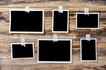 Paper blank photo frames hanging on wooden wall