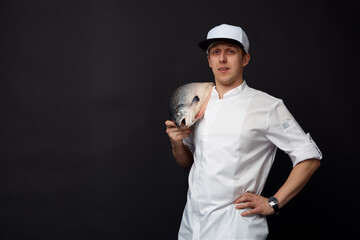 Naklejka premium Chef cook holding a big atlantic salmon fish on his shoulder solated on black background