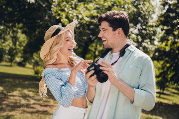 Portrait of two attractive cheerful glad couple choosing captures of model portfolio laughing having fun outdoors