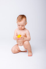 Fototapeta na wymiar cute baby girl in a diaper playing with a rubber toy duck isolated on a white background