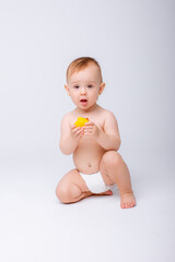 Fototapeta na wymiar cute baby girl in a diaper playing with a rubber toy duck isolated on a white background